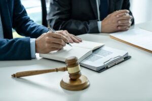 Business professionals and a male lawyer consult with a client during a team meeting in a law firm office, representing the concept of legal services and collaboration.