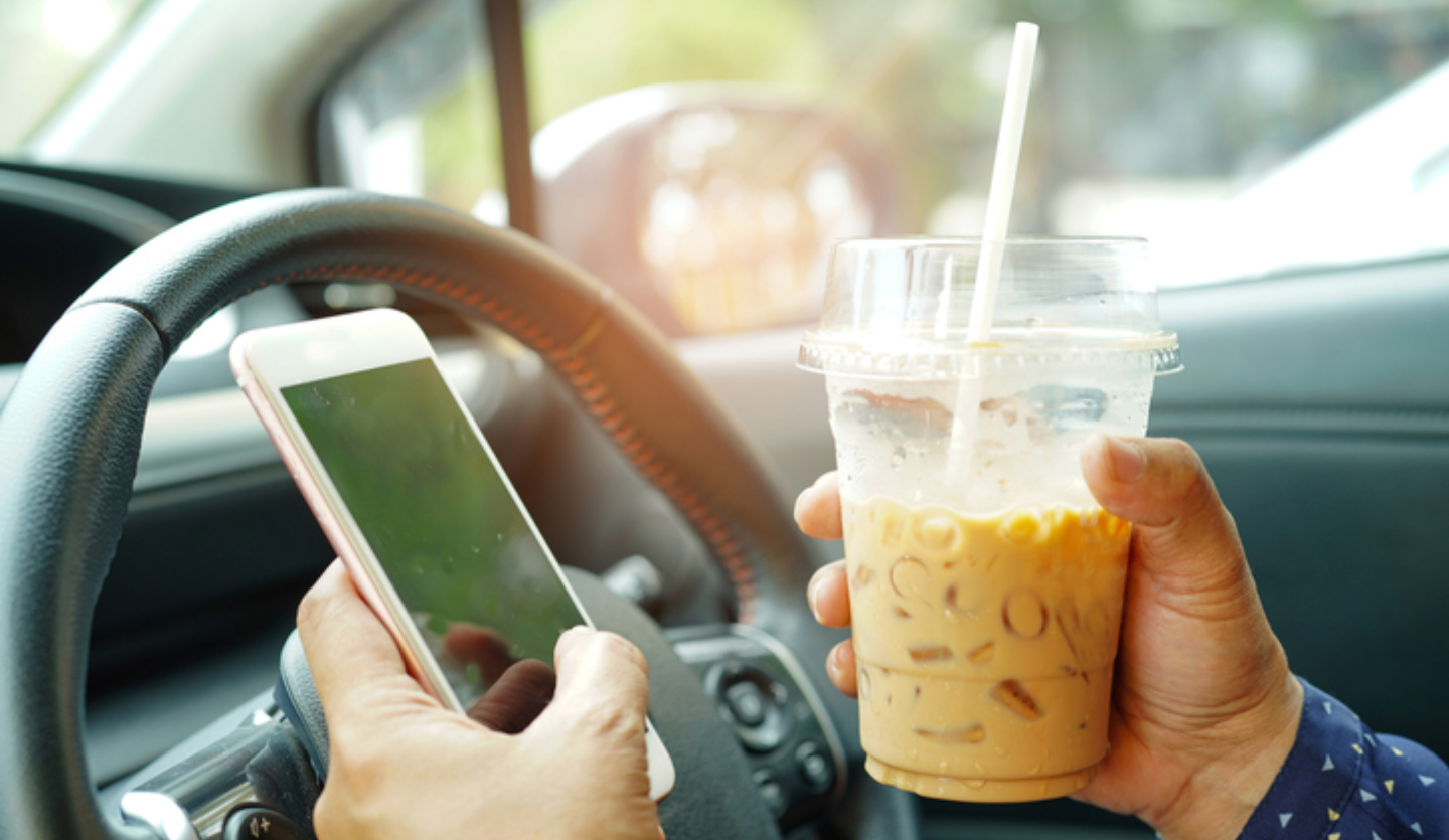 driver drinking coffee and on their phone