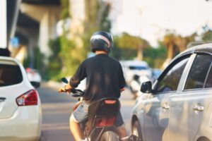 motorcyclist riding between lanes of slow-moving or stopped traffic.