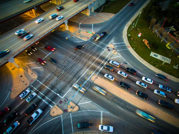 Aerial drone shot of a busy intersection car zooming and fading out of frame