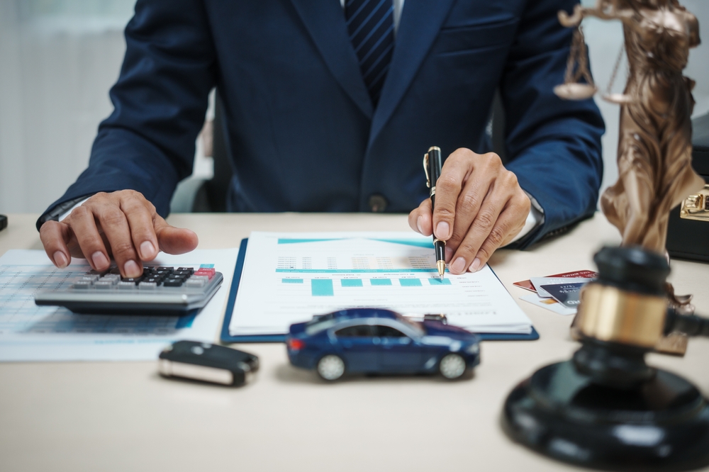 A man in a suit sells cars at his desk, offers online car insurance, car loans, comprehensive coverage, cash withdrawals via credit cards, and provides free legal advice.