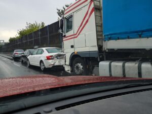 Truck collides with passenger car on a rainy highway, captured from a passing vehicle.