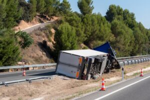 Refrigerated semi-trailer truck overturned in the median near a highway exit.