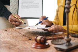 A lawyer reviews a contract with a client in an office, with legal documents spread across the table.