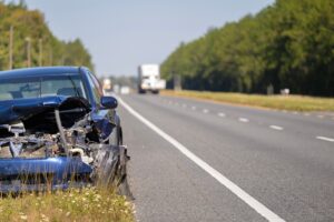 A crashed car, damaged in a traffic accident on one of the major highways or expressways, sits abandoned on the roadside.