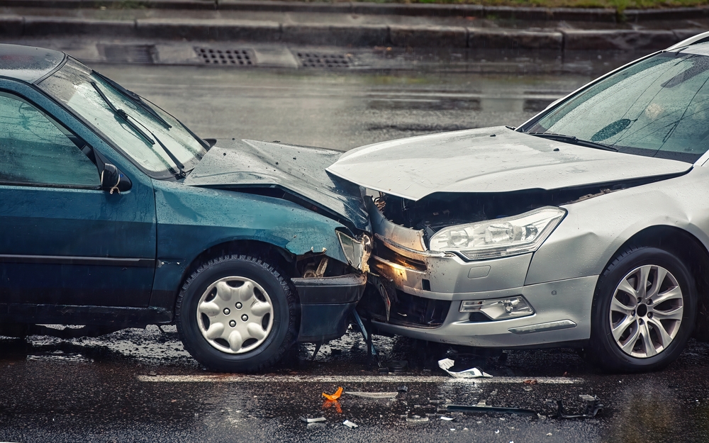 Head-on collision on a wet road during rain. Two damaged cars after a car crash, side view.