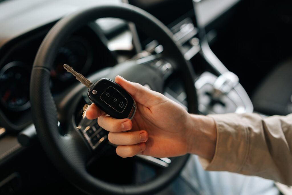 Hand holding a car key inside a modern vehicle.