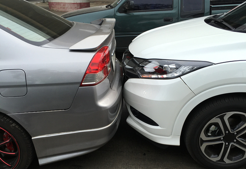 White car colliding with the back of a silver car in a rear-end accident.