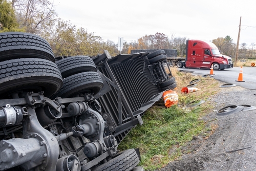 Overturned semi-truck on a rural Albany roadway with another truck stopped nearby, showing a serious crash scene relevant to an Albany truck accident lawyer.