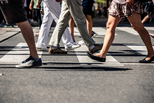 Crowd of people walking through a busy crosswalk, a common scenario handled by a Buffalo pedestrian accident lawyer.