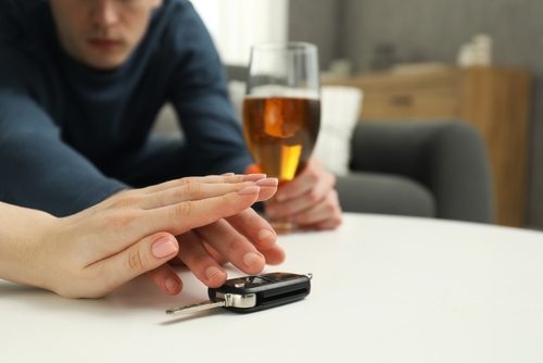 Person stopping someone holding a beer from taking car keys.