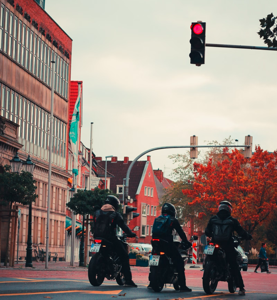 Motorcyclists waiting at a red light on an autumn city street, reflecting riding conditions in Buffalo and Erie County, New York